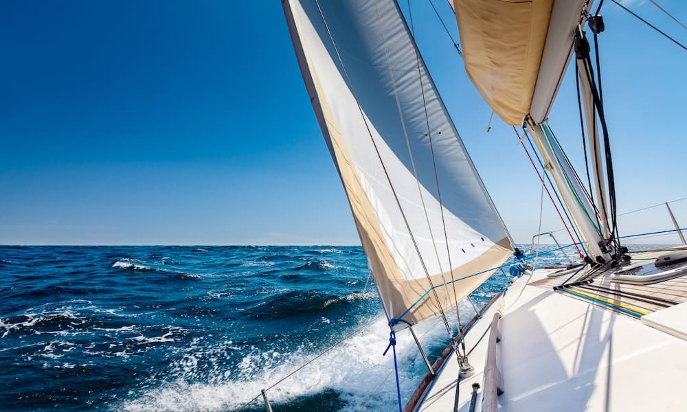 White sailing boat at open sea in sunshine